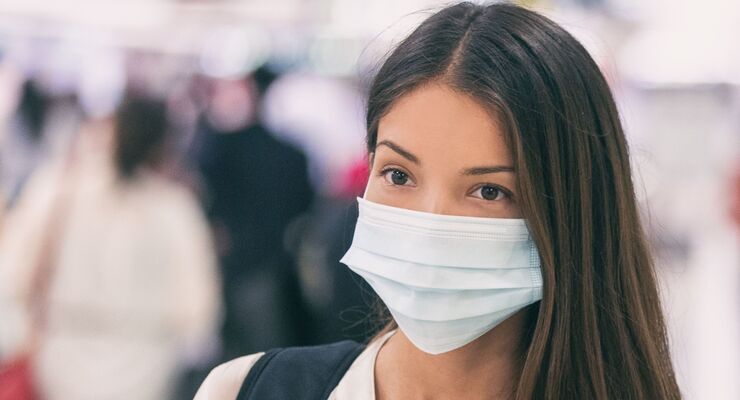 Coronavirus corona virus Asian woman wearing flu mask walking on work commute in public space transport train station or airport panoramic banner.