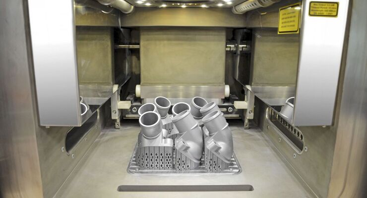 Mercedes-Benz Lkw ist weltweit Technologieführer beim Einsatz von 3D-Druckteilen und produziert künftig auch komplexe metallische Ersatz- und Sonderbauteile in höchster Qualität. Der Blick in den Innenraum des 3D-Druckers zeigt die ersten gedruckten Thermostatabdeckungen, die noch mit der Bauplattform verbunden sind. Nach dem Entfernen von Plattform und stützender Struktur wird das abgesaugte, gesiebte und gereinigte Aluminium-Silizium- Metallpulver ökologisch der Wiederverwendung zugeführt. 

Mercedes-Benz Trucks is the worldwide technological leader in the use of 3D printed components, and will in future also produce complex metallic spare and special parts in first-class quality. The view into the interior of the 3D printer shows the first printed thermostat covers, which are still connected to the work platform. After removal of the platform and support structure, the aluminium/silicon metallic powder is removed by suction, sieved, cleaned and ecologically fed back into the recycling system.